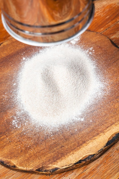 Flour sifting through sifter on wooden board