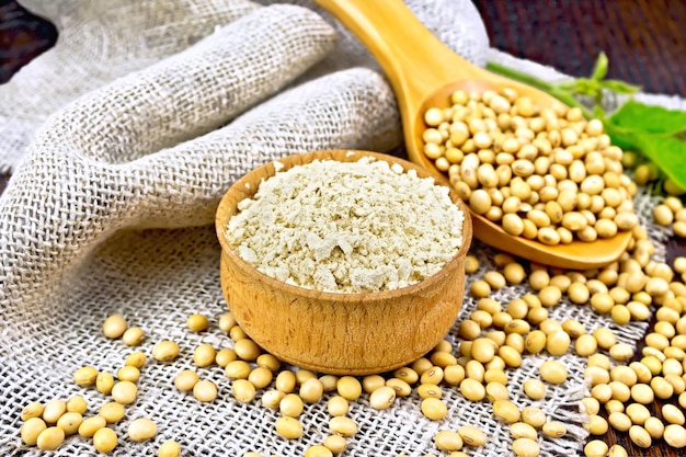 Photo flour soy in bowl with soybeans on board