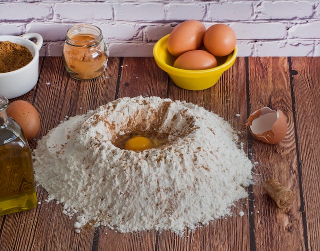 Flour volcano with egg on wooden table