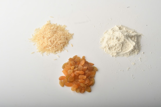 Farina, grano, riso, uvetta e monete su sfondo bianco