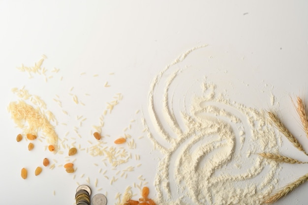 Flour, wheat, rice, raisins and coins on a white background