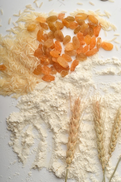 Мука, пшеница, рис, изюм и монеты на белом фоне