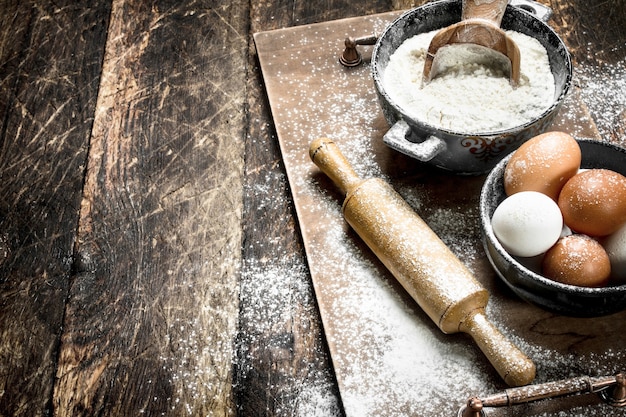 Flour with fresh eggs. On a wooden background.