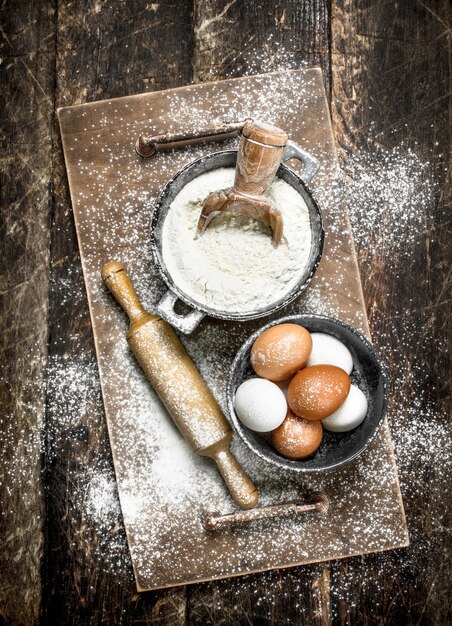 Flour with fresh eggs. On a wooden surface.