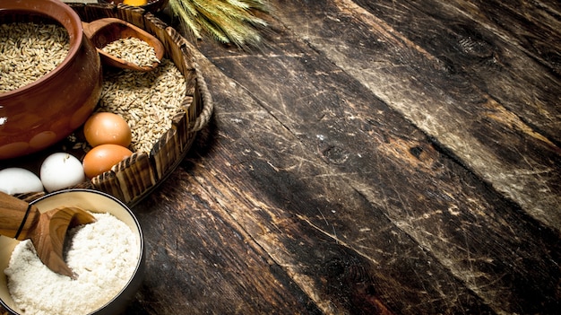 Flour with wheat grains on an old tray. On a wooden background.