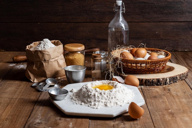 Photo flour with yolk egg and a lot of eggs put in the basket are place on the wooden table for cooking