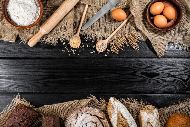 小麦、卵の小穂と暗い木製のテーブルの上に木製のボウルに小麦粉します。