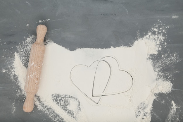 Photo flour and wooden rolling pin on a gray background.