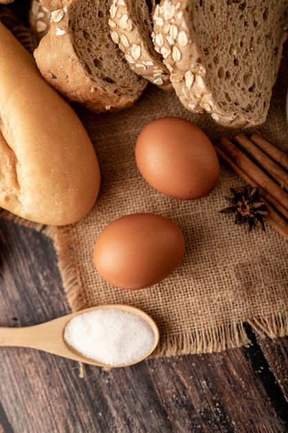 Flour in wooden spoon and eggs on the sack