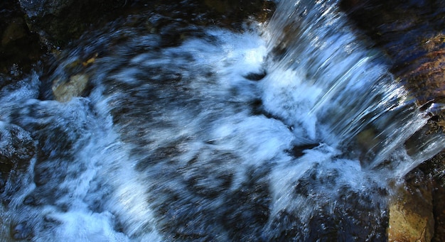 Foto il flusso dell'acqua in una piccola cascata nella vista dall'alto del torrente di montagna