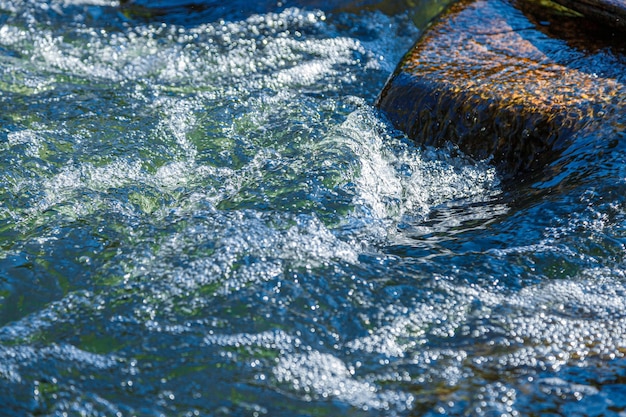 Foto flusso d'acqua e spruzzo da una pietra vicino