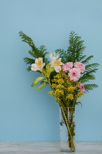 Foto composizione floreale in un vaso di vetro con sfondo blu elegante concetto di decorazione d'interni