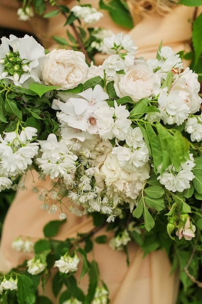 ドレスに白い花のフラワーアレンジメント。花嫁はウェディングブーケを握る