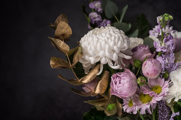 Flower arrangement with golden decorative leaves on black background