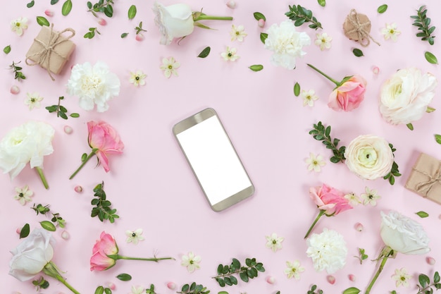 Flower arrangement with a mobile phone in a floral frame, top view and flat lay