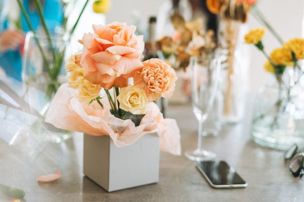 Flower arrangement with yellow and pink roses in gift box on table in flower shop modern floristic