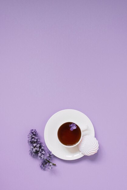 Flower arrangements of beautiful purple lilac on a purple background with a cup of tea