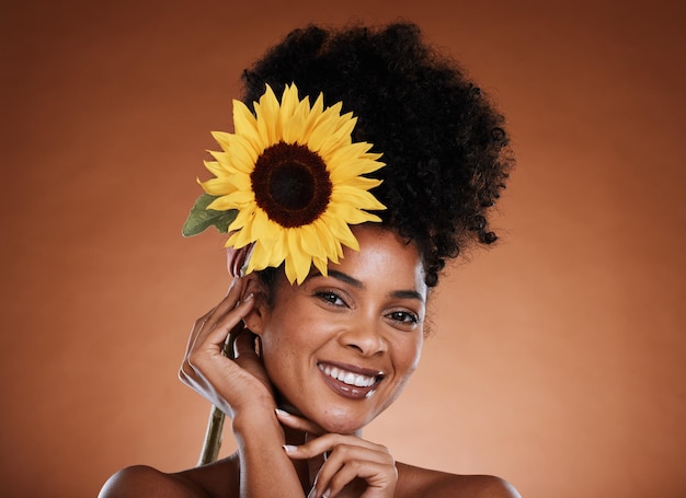 Flower beauty and woman or portrait for skincare haircare and natural health or wellness Sunflower nature and black woman on a brown studio background for organic skin care or bodycare