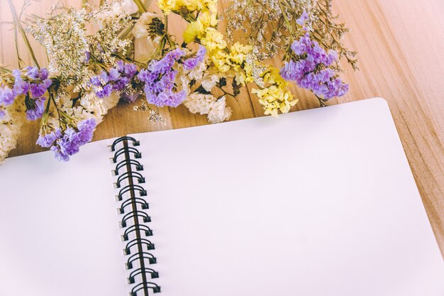 flower blossom and white blank notebook on wooden table