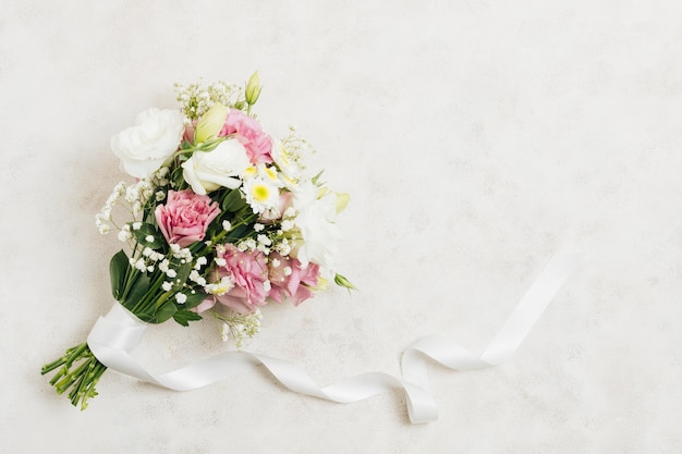 Flower bouquet tied with white ribbon on white backdrop