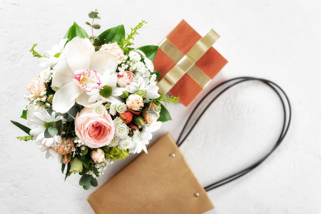 Фото Букет цветов с подарочной коробкой и сумкой на белом фоне плоская планировка, вид сверху цветочные день святого валентина или день матери концепции