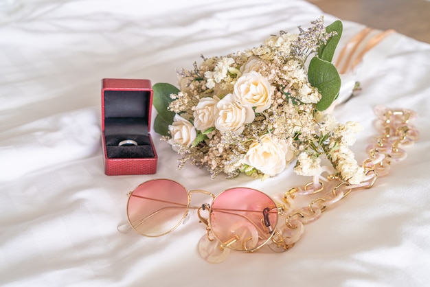 Foto bouquet di fiori con occhiali da sole e anello