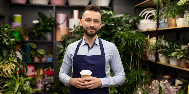 Flower business owner surrounded by potted plants looking at the camera with a smile