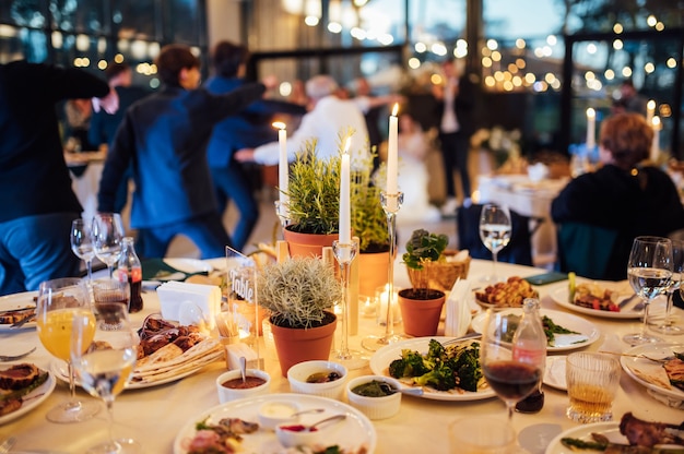 Photo flower and candle decoration for a wedding against the background of dancing guests