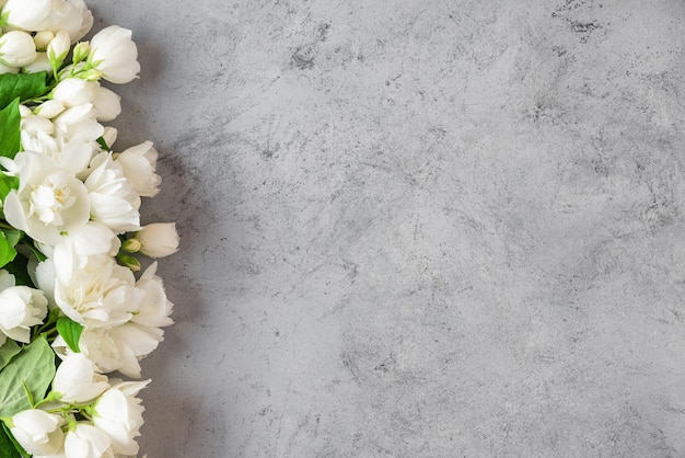 Фото Цветочная композиция белые ясминные цветы на сером бетонном фоне плоский вид свадьбы или