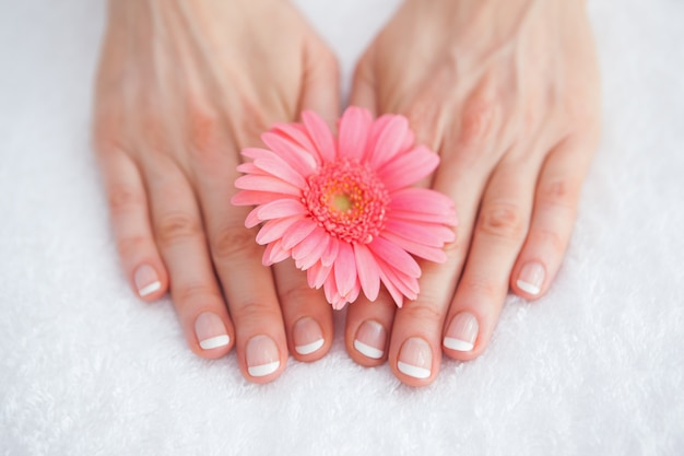 Photo flower on french manicured fingers at spa center