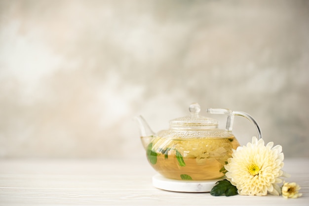 Photo flower herbal tea with chrysanthemum petals in a glass teapot, close-up