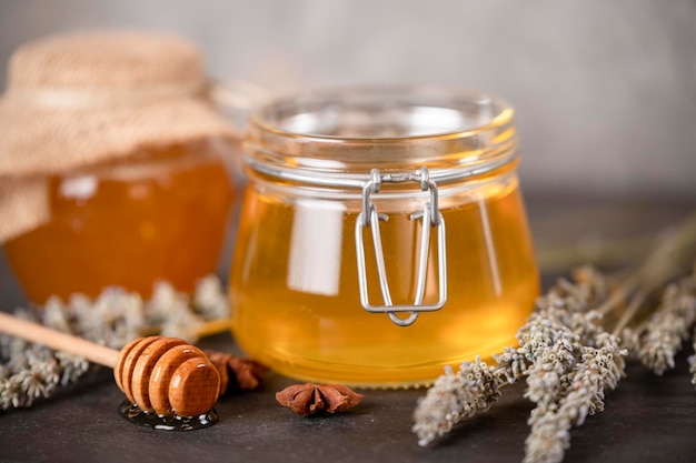 Flower honey in jars, and a wooden spoon for honey on a dark background