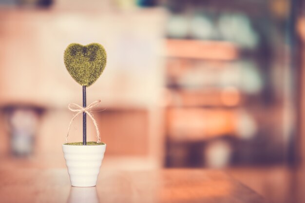 Flower Pot with green heart on the wood table with bokeh and copy space