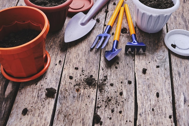 Flower pots and set decorative gardening tools shovel rake and pitchfork on a wooden background