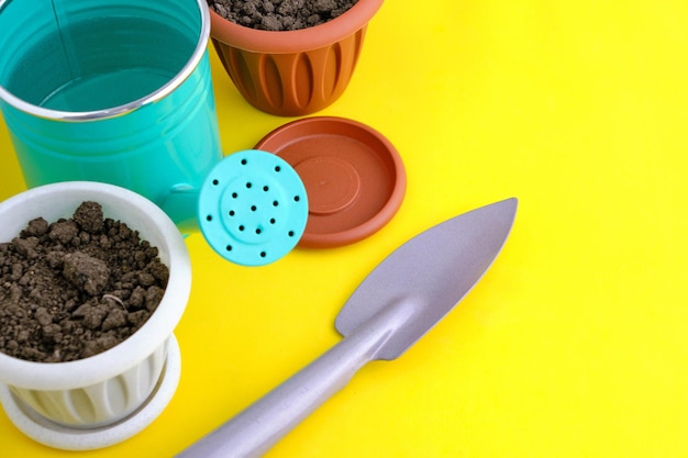 Flower pots watering can and garden tool bright yellow background