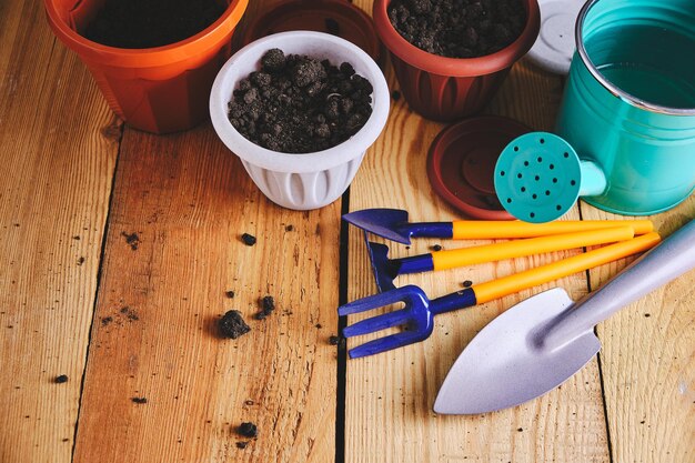 Flower pots watering can and garden tool on a wooden background