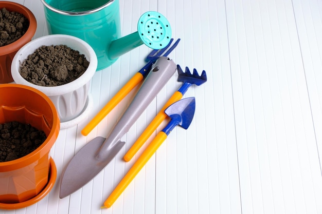 Flower pots watering can and garden tools on white countertop