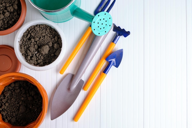 Flower pots watering can and garden tools on white countertop