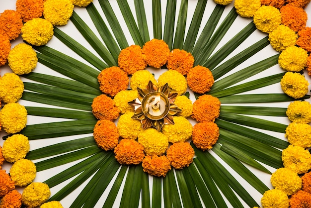 マリーゴールドまたはゼンドゥの花とバラの花びらを使用して作られたディワリ祭またはポンガル祭のフラワーランゴーリー、ムーディーまたは白い背景、選択的なフォーカス