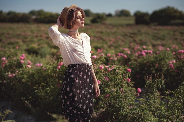 Flower series free time of summer Provence books reading at sunset for a bottle of red wine young woman walking near blooming rose bushes