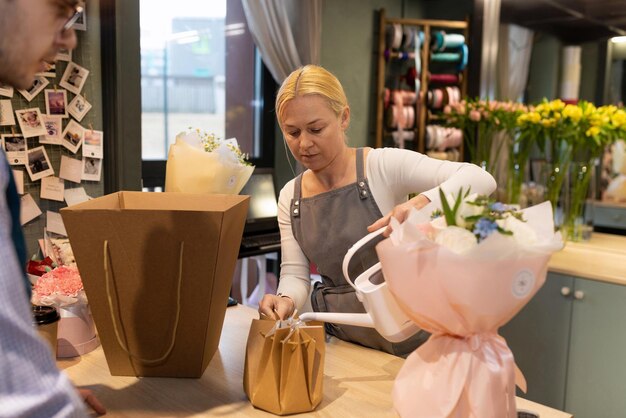 Flower shop employee pouring water into a flower carrier