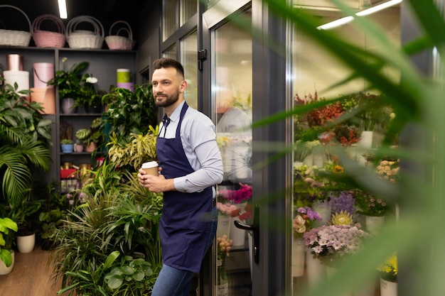 Flower shop employee resting between orders leaning on the refrigerator