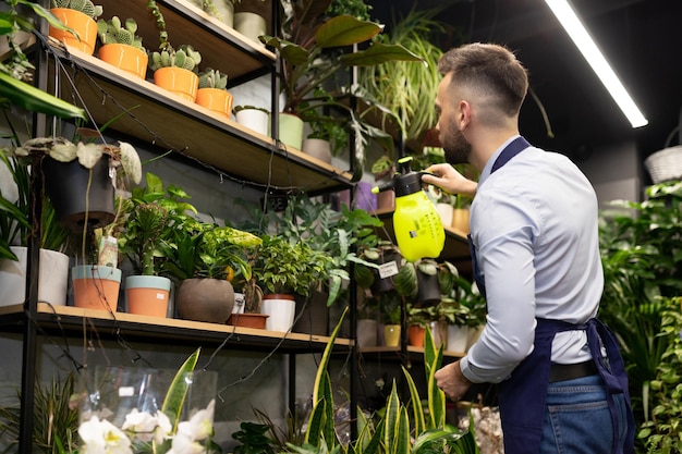 Flower shop worker watering flowers and potted plants