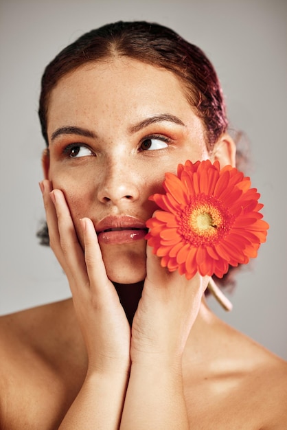 Flower skincare and glow of a woman with hands on face for dermatology makeup and cosmetics Facial wellness and self care for natural skin floral product and a healthy model thinking in studio