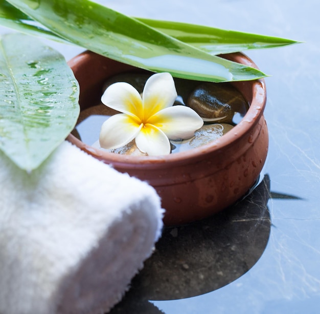 Flower towel and stones treatment on dark background