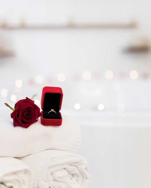 Фото Цветок, полотенца и кольцо в шкатулке возле спа-ванны со свечами