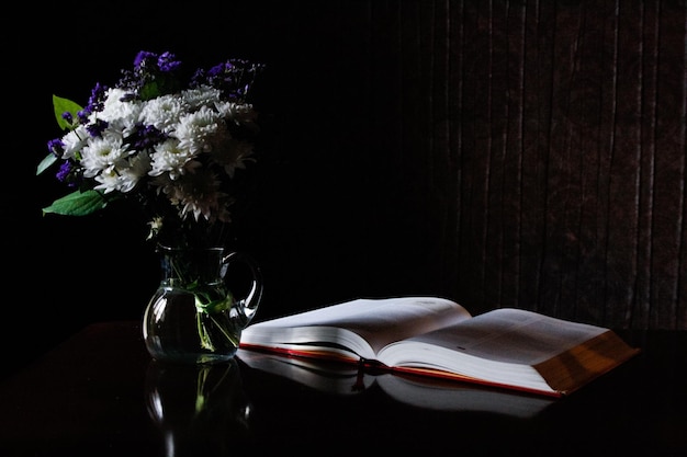 flower vase and open book on table at home