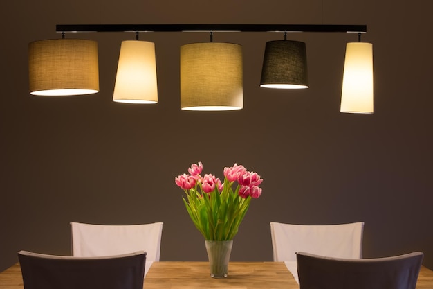 Photo flower vase on table against illuminated wall at home