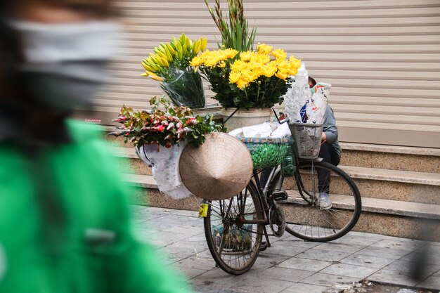 Photo a flower vendor in old quarter hanoi taking a break on the side of a busy street