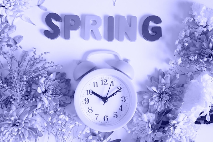फोटो flowers, alarm clock and inscription spring on very peri color trend 2022background top view waiting for spring concept
